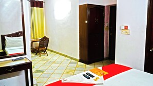 A hotel room with a bed, a desk, a chair, a wardrobe, and a bathroom door. - Roomshala Hotel Iconic Near Karol Bagh (New Delhi)