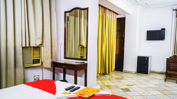 A hotel room with a bed, a desk, a mirror, a television, and a radiator. - Roomshala Hotel Iconic Near Karol Bagh (New Delhi)