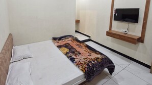 Un dormitorio con una cama, un ventilador de techo, un televisor montado en la pared y una alfombra estampada.