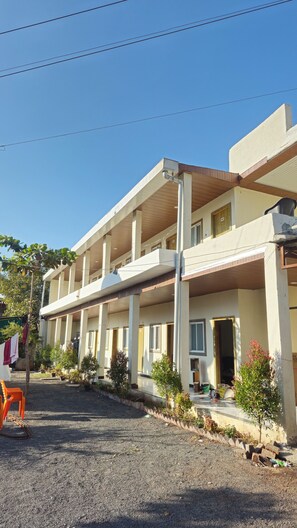 Un edificio de varios pisos con un espacio al aire libre techado, columnas y plantas en macetas.