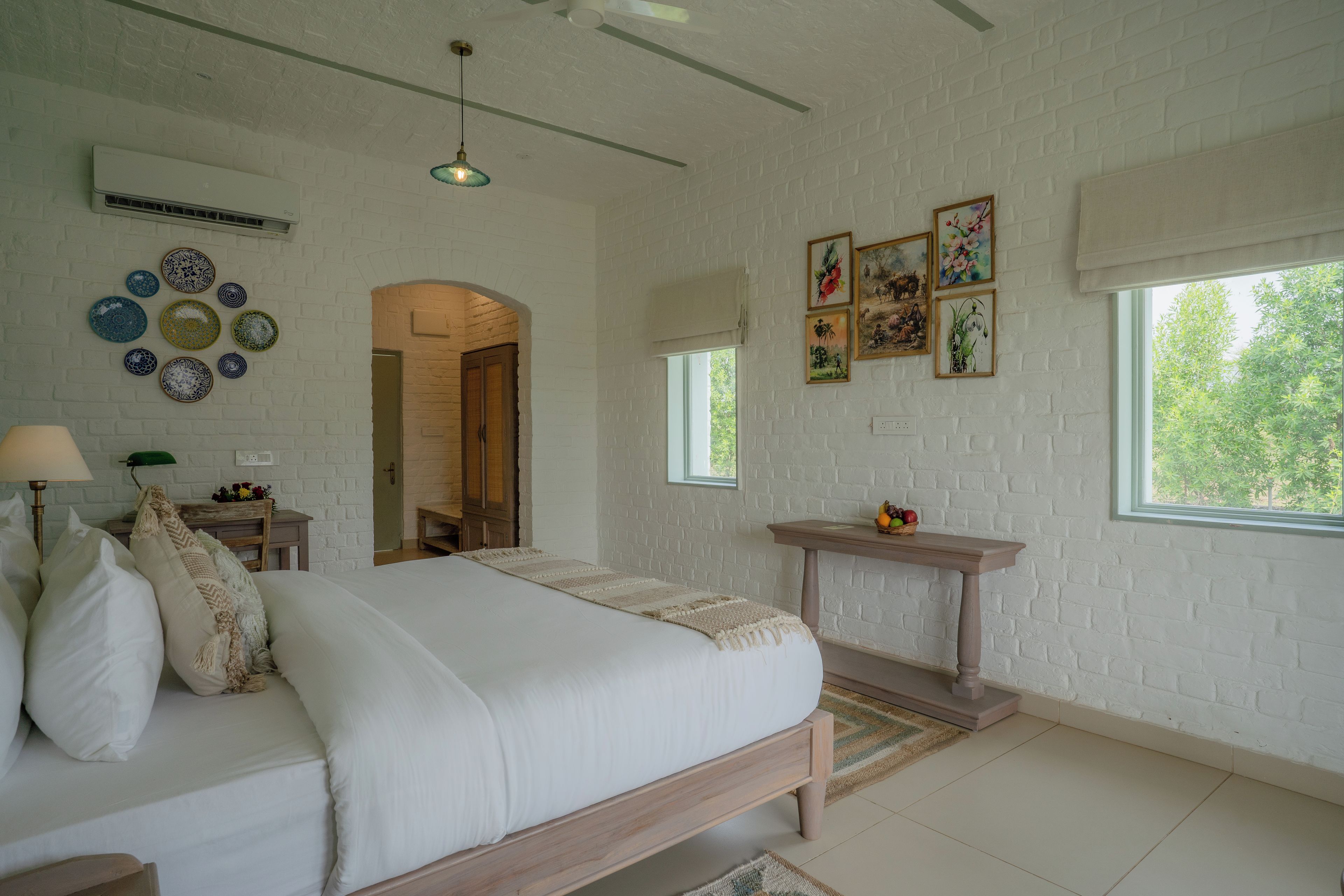 A bedroom with a bed, bedside table, wall decor, and a window.