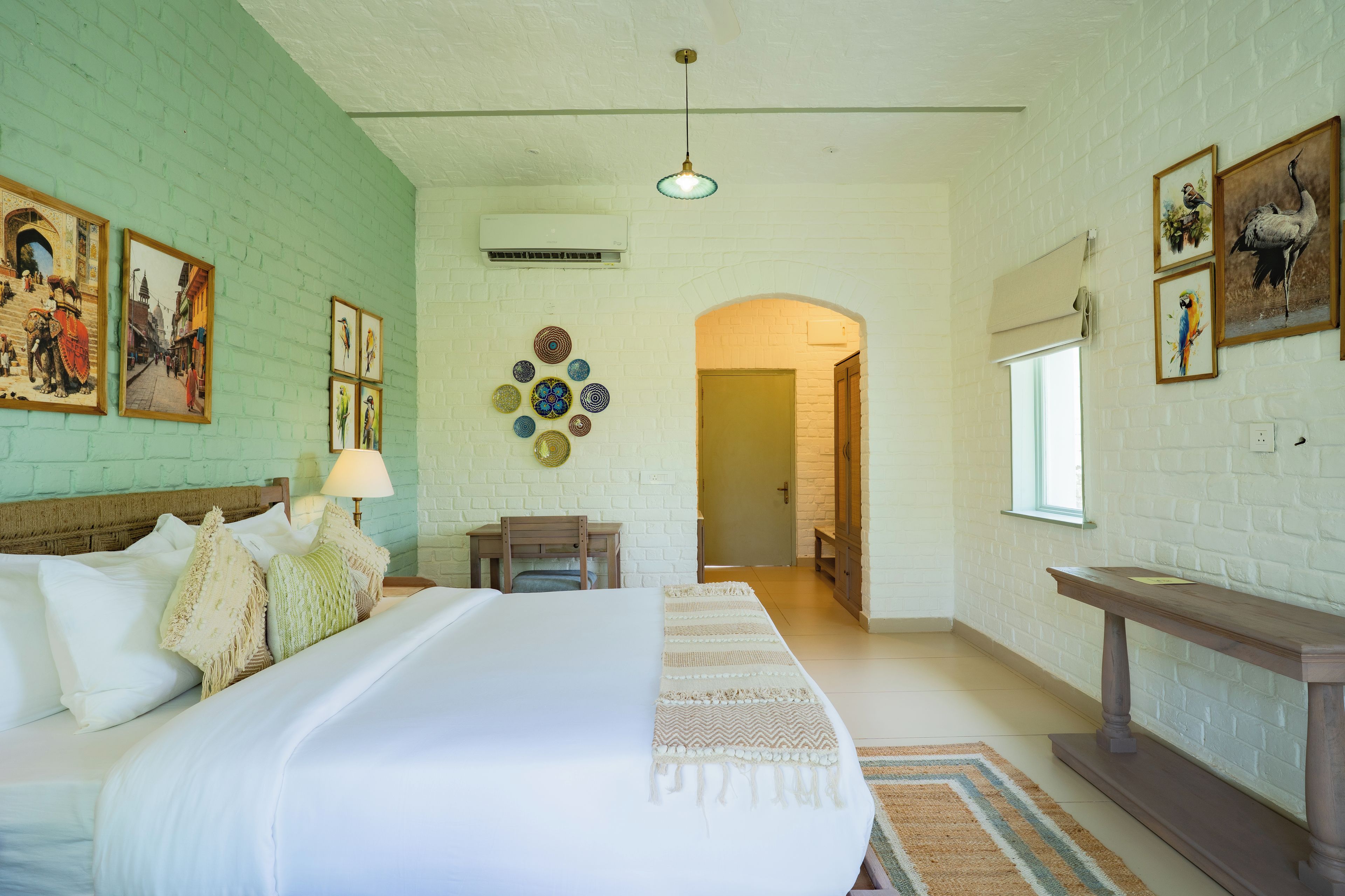 A hotel room with a large bed, a desk, and a view of the hallway.