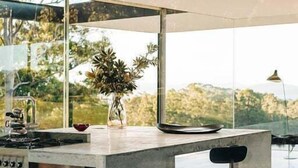 A modern kitchen with a large island, a gas stove, and a view of the outdoors. - Triptych - The Glass House (Tasman)