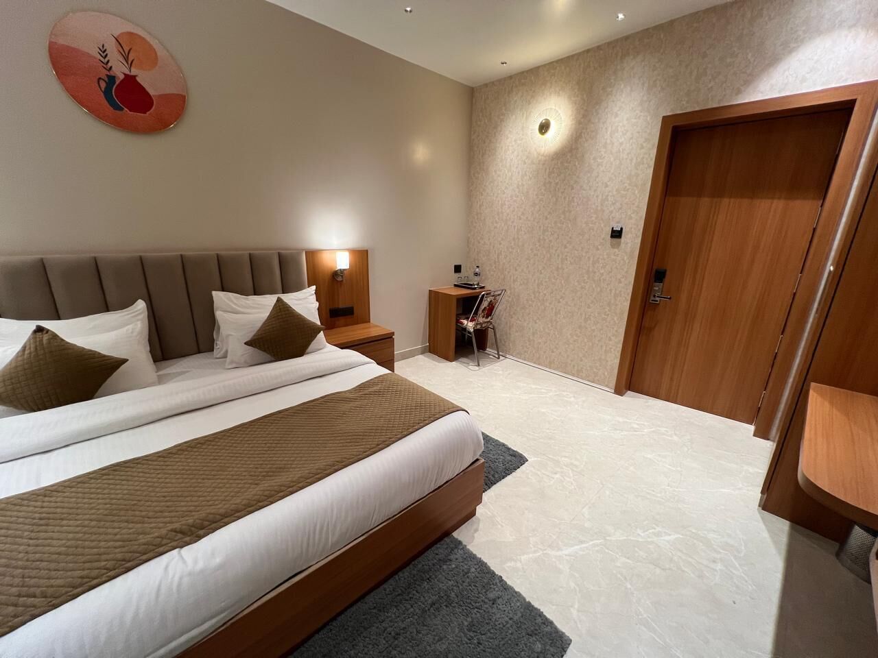Una habitación de hotel con una cama grande, mesitas de noche, un escritorio y un armario.