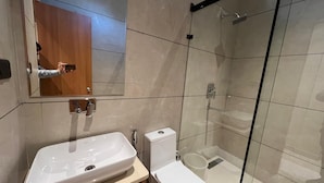 Un bagno moderno con cabina doccia in vetro, lavandino bianco e water.
