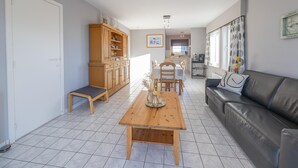 A modern living room with a wooden dining table, a leather sofa, and a built-in wooden cabinet. - Bright apartment with 2 bedrooms and garage (Middelkerke)