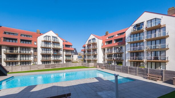 A modern hotel with a swimming pool, multiple balconies, and a well-maintained lawn. - Bright apartment with 2 bedrooms and garage (Middelkerke)