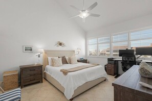 Un dormitorio con cama, mesitas de noche, un escritorio y un ventilador de techo.