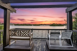 A wooden deck with two benches overlooking a body of water during sunset. - Top-Floor Sky Loft | 22’ Ceilings | Private (Sarasota)