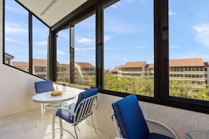 Ein Balkon mit Tisch und Stühlen, große Fenster mit Blick auf Gebäude und Grünflächen.