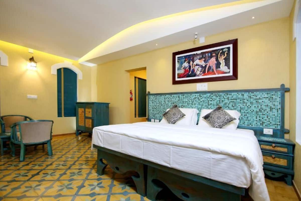 Una habitación de hotel con una cama, una mesita de noche, una silla, un cuadro en la pared y un suelo de baldosas.