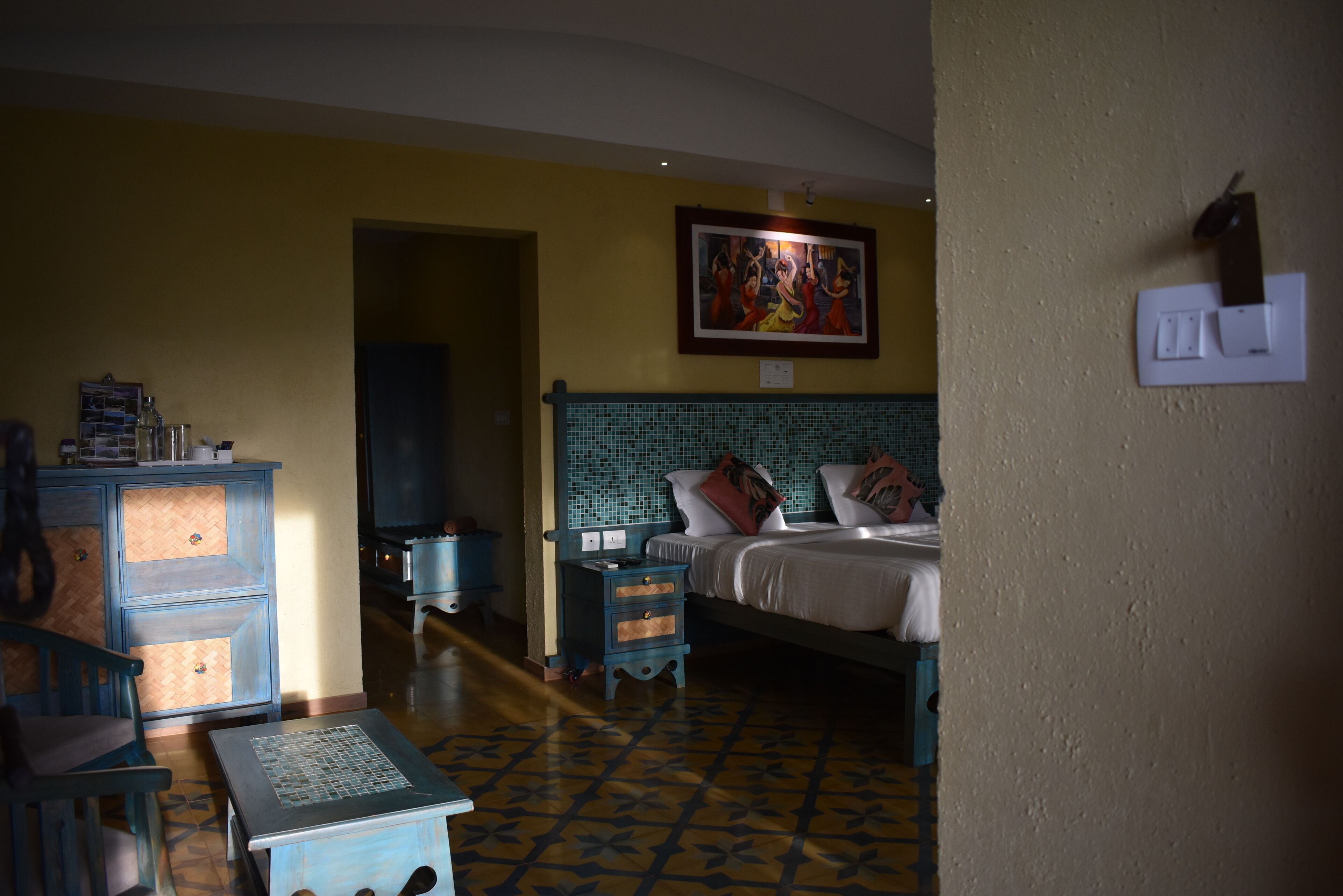 A room with a bed, a nightstand, a dresser, and a tiled floor.