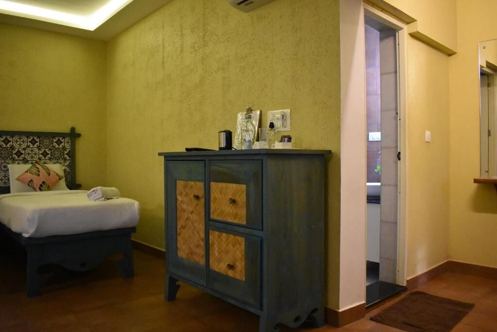 A bedroom with a bed, a dresser, and a door leading to another room.