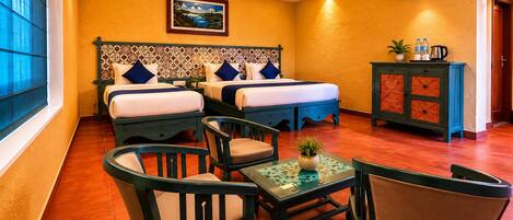 A hotel room with two beds, a ceiling fan, an air conditioner, a cabinet with toiletries, and a window with curtains.