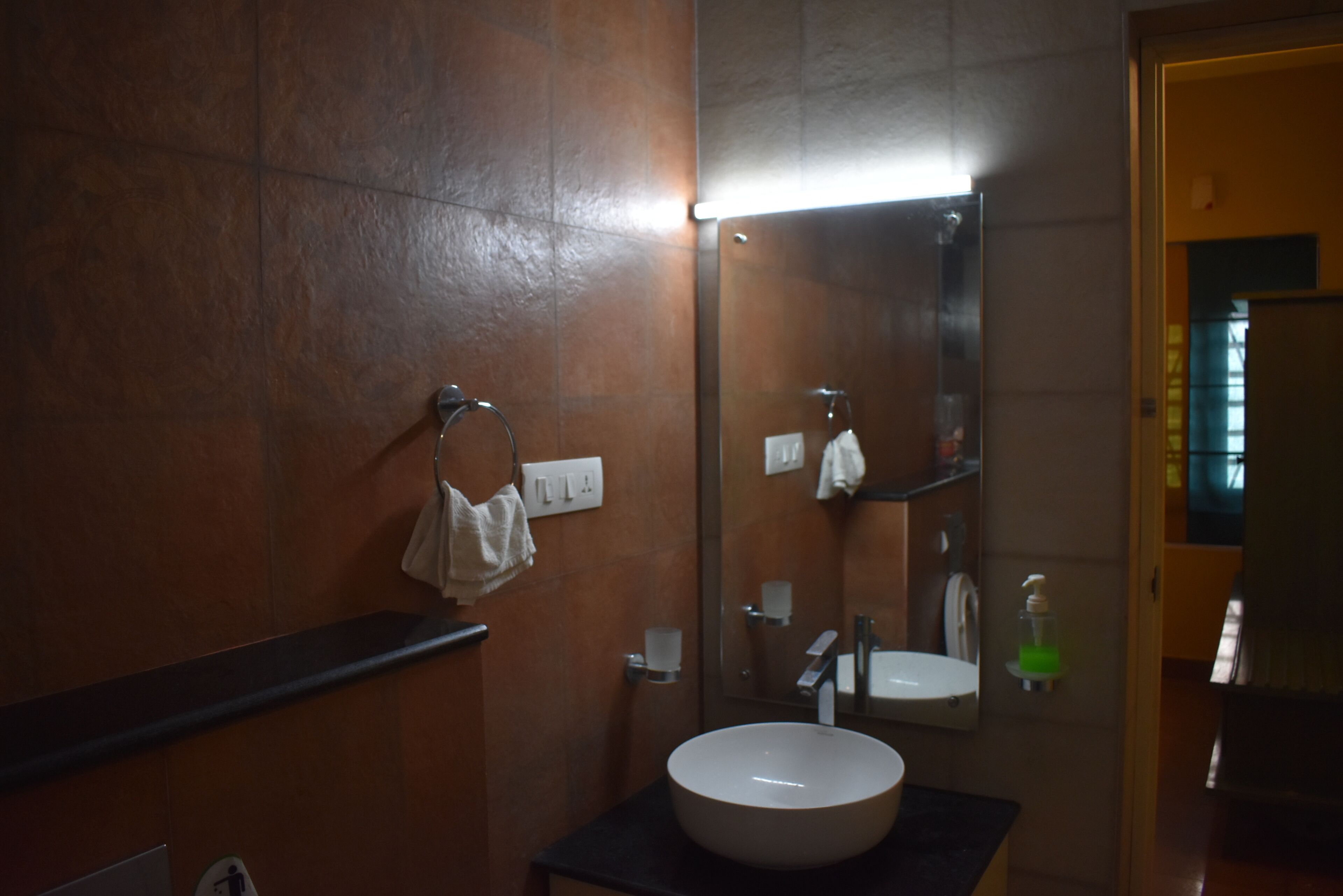 A bathroom with a sink, mirror, towel rack, and soap dispenser.