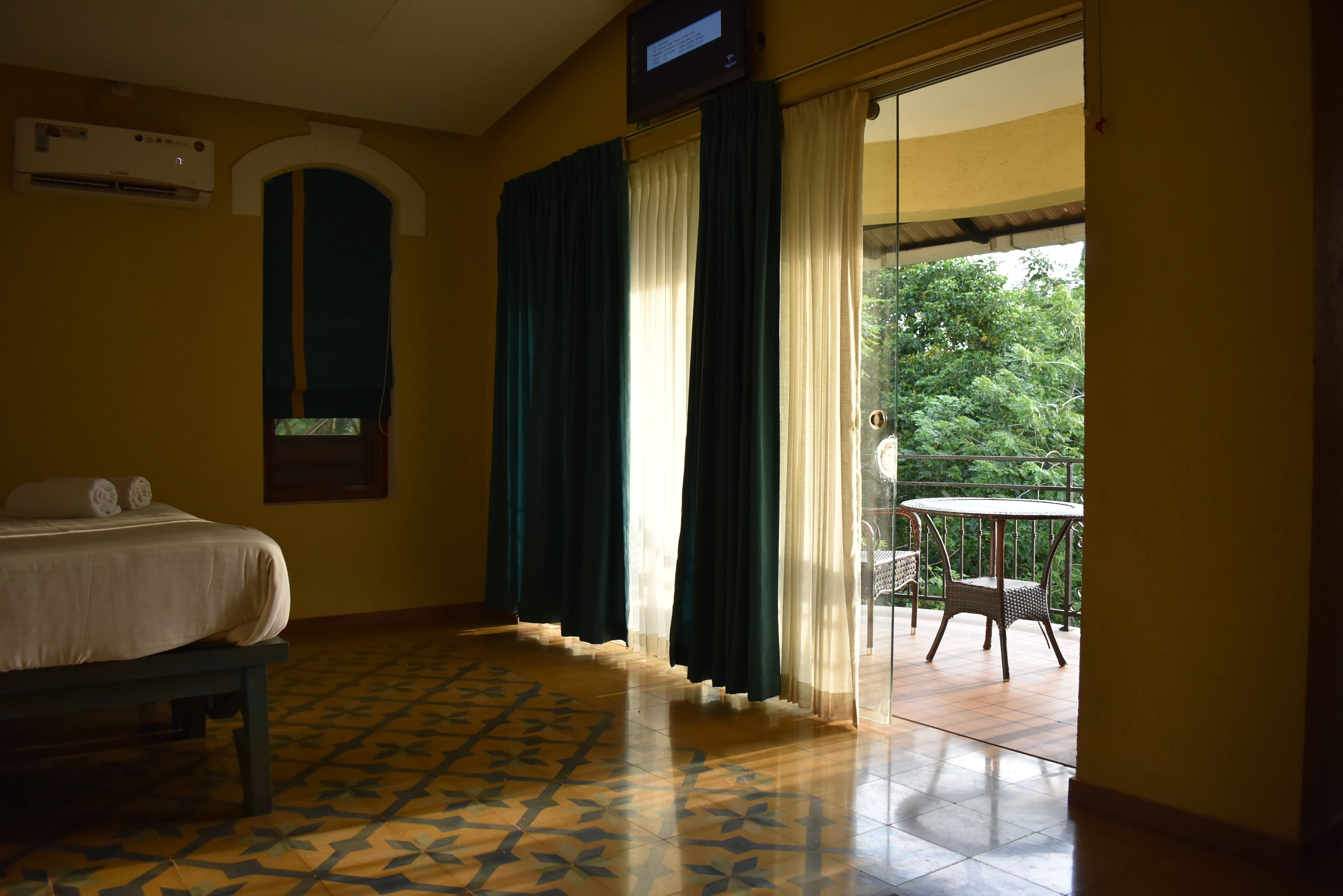 Habitación de hotel con cama, una mesita y balcón con una silla.