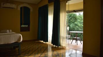 Habitación de hotel con cama, una mesita y balcón con una silla.