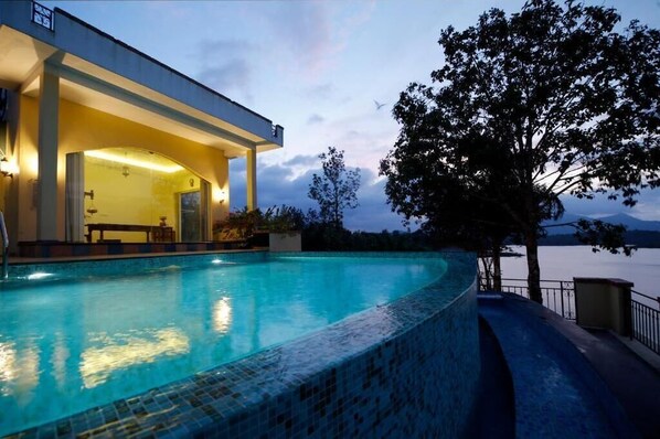 A swimming pool with a covered area and a view of a body of water.