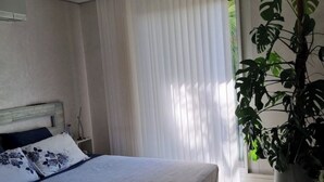Une chambre à coucher avec un lit, des rideaux et une plante en pot.