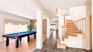 A spacious room with a pool table, a staircase, and a view of the backyard. - StayAU Family Haven Pet-Friendly (Caroline Springs)