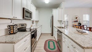 A modern kitchen with white cabinetry, stainless steel appliances, and a granite countertop. - 1 Mi to FSU: Group-Friendly Midtown Getaway! (Tallahassee)