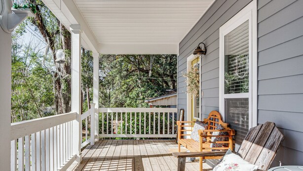 A wooden porch with a white railing, a wooden bench with cushions, and a table. - 1 Mi to FSU: Group-Friendly Midtown Getaway! (Tallahassee)
