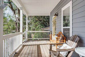 A wooden porch with a white railing, a wooden bench with cushions, and a table. - 1 Mi to FSU: Group-Friendly Midtown Getaway! (Tallahassee)