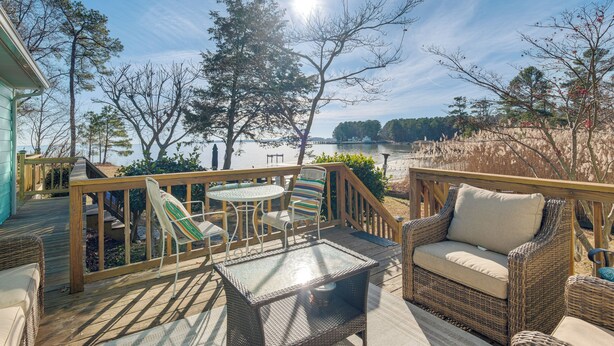 A wooden deck with outdoor furniture, including a wicker sofa and chairs, overlooking a body of water. - Potomac River Haven w/ Private Beach, Dogs Welcome (Hague)