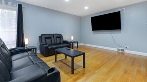 A living room with a sofa, a coffee table, a TV, and a lamp. - Spacious Family Home with Game Room, 3 Beds 2 Bath (Elgin)