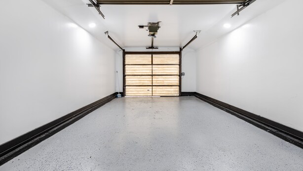 A spacious, empty garage with a concrete floor, metal ceiling, and a large garage door. - Spacious Family Home with Game Room, 3 Beds 2 Bath (Elgin)