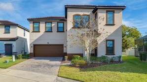 A two-story residential building with a garage, a small tree, and a well-maintained lawn. - Golf, Dine & Unwind Poolside! Haines City Getaway (Haines City)