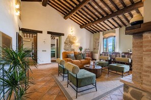 A spacious living area with a high wooden ceiling, stone wall, and a view of the outdoors. - Welcoming country house in Tuscany Beautiful, private fenced-in pool Wine, oil and Chianina beef... (Montenero)