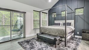 Ein Schlafzimmer mit Himmelbett, einer Bank und einem großen Fenster mit Jalousien.