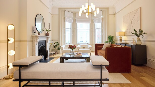 A living room with a fireplace, a bench, a red sofa, and a coffee table. - Kensington Five-Bedroom Townhouse (London)