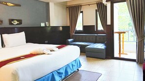 Une chambre d’hôtel avec un grand lit, un canapé, un balcon avec des rideaux et une vue sur la verdure environnante.