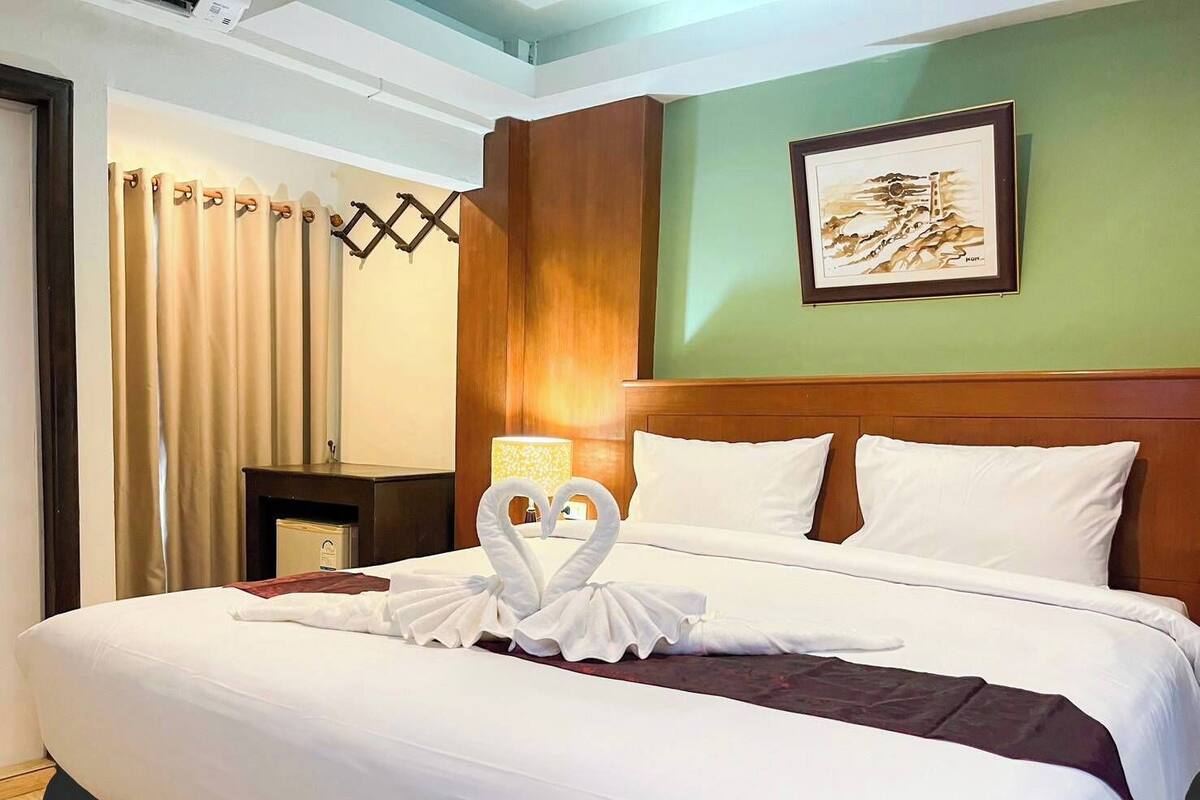 Une chambre d’hôtel avec un grand lit, une tête de lit, une table de chevet, une lampe et un tableau au mur.
