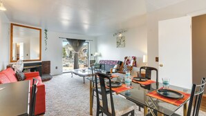 A spacious living room with a glass dining table, red sofa, and a fireplace. - Adventure Base 3 Near Lake Powell - Dog Friendly (Big Water)