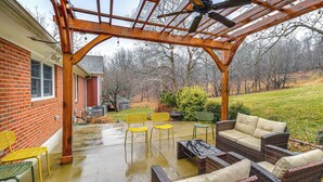 Een terras buiten met rieten meubilair en een pergola.