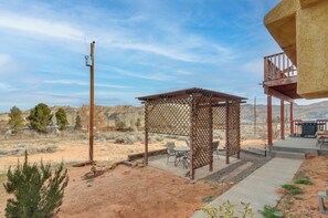 A covered outdoor seating area with a pergola, a barbecue grill, and a view of a desert landscape. - Adventure Base 2 Near Lake Powell (Big Water)