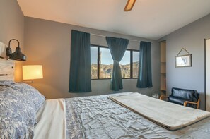 A hotel room with a bed, a desk, a chair, a lamp, and a window with curtains. - Adventure Base 2 Near Lake Powell (Big Water)