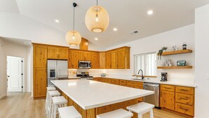 A modern kitchen with wooden cabinets, a large island with bar stools, a microwave, and a dishwasher. - Golf & Hike! Home in Lake Almanor West Community (Chester)
