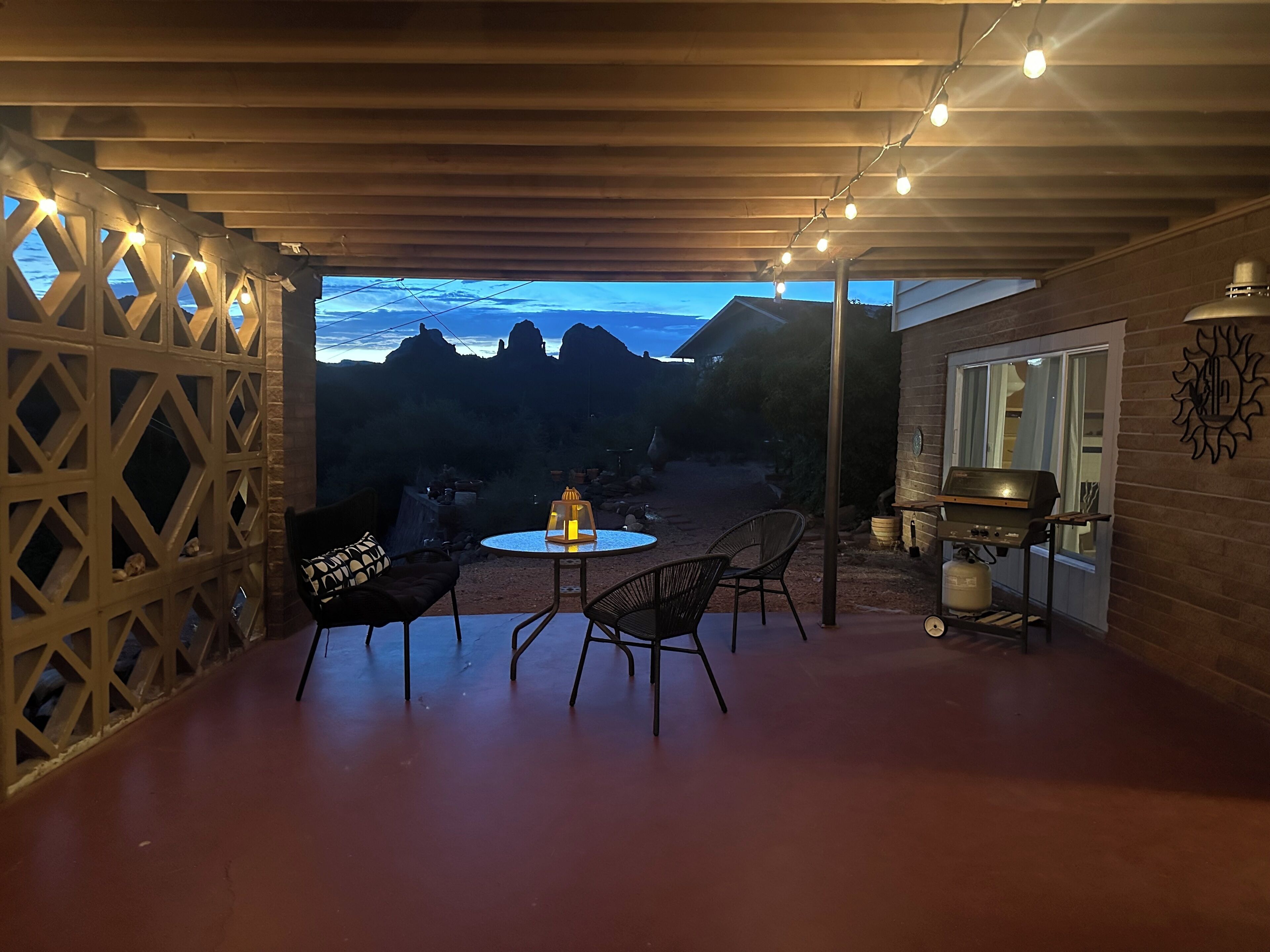 Una terrazza esterna con un tavolo rotondo e sedie, un barbecue e vista sulle montagne.