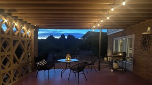 Une terrasse extérieure avec une table ronde et des chaises, un barbecue et une vue sur les montagnes.