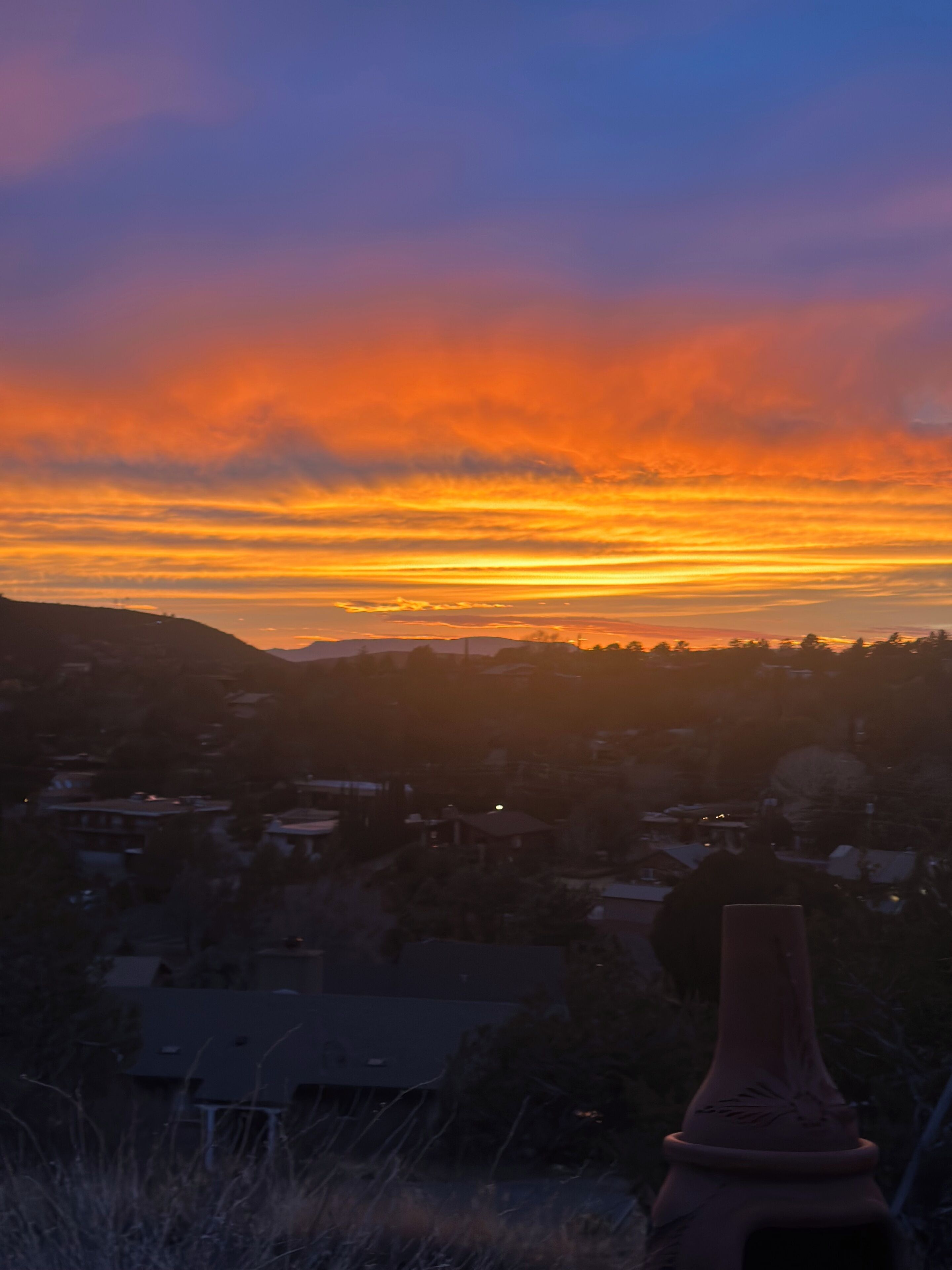 Un atardecer sobre una zona residencial con casas y una colina al fondo.
