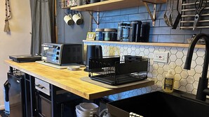 Une cuisine de taille réduite, dotée d’un plan de travail en bois, d’un évier noir et de divers appareils de cuisine.