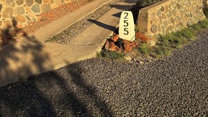 Une maison moderne avec un mur de soutènement en pierre, une allée et une plaque portant le numéro « 255 ».
