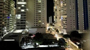 A nighttime view of a high-rise residential building complex with multiple floors and balconies, surrounded by other buildings and a street with parked cars. - Holiday and rest apartment near the sea (Cartagena de Indias)