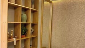 A corner room with a wooden shelving unit containing various decorative items and a textured wall. - Holiday and rest apartment near the sea (Cartagena de Indias)