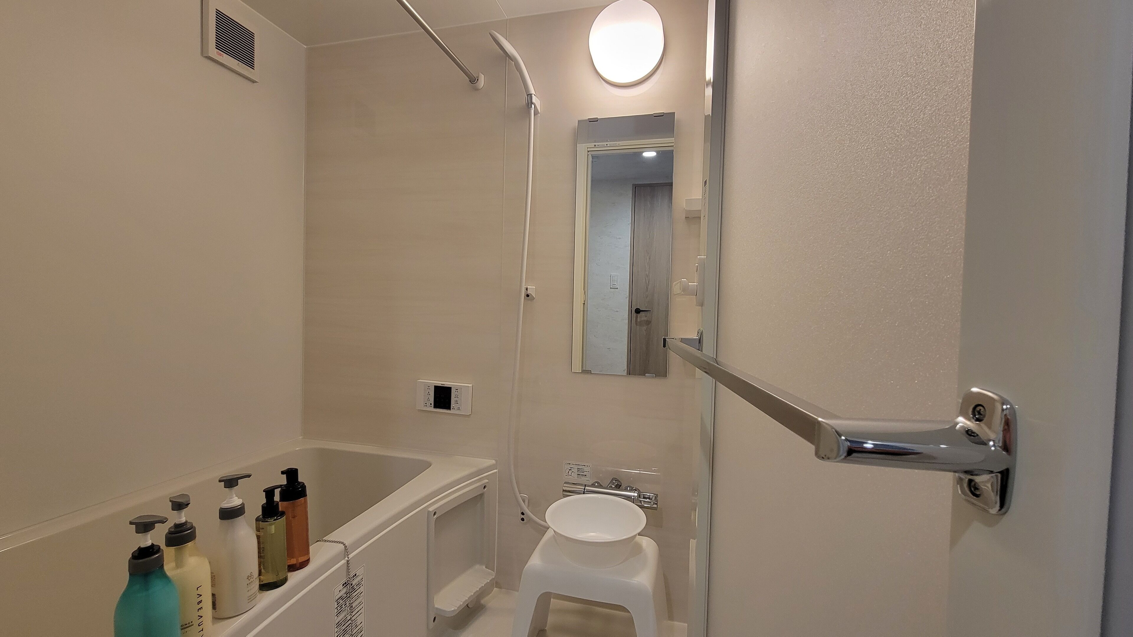A modern bathroom with a bathtub, a sink, and a shower. There are toiletries on the side of the tub.