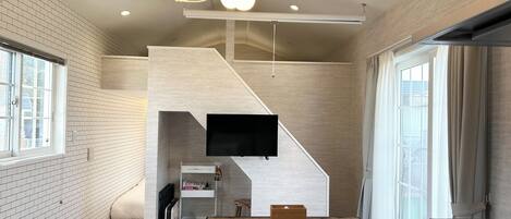 Un interior moderno con una escalera, un televisor de pantalla plana y una zona de comedor.
